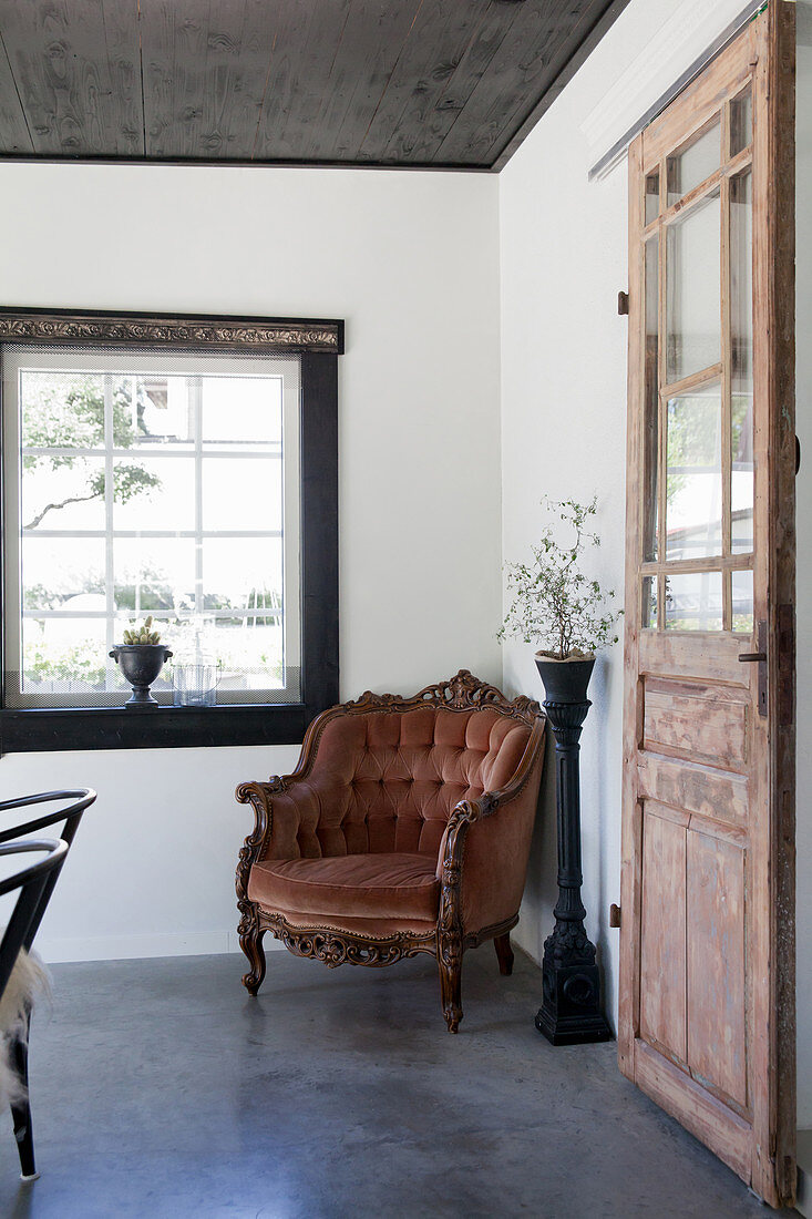 Alter rostfarbener Samt-Sessel neben einer Holztür