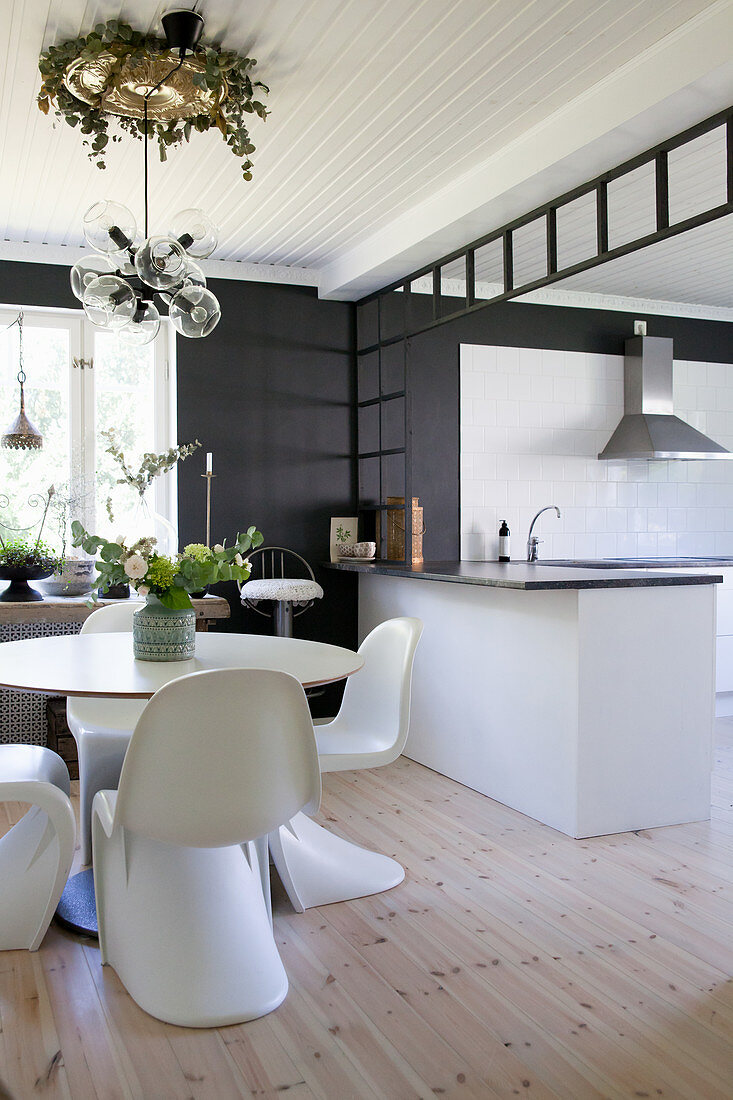 Esstisch mit Designerstühlen vor der offenen Küche in Weiß