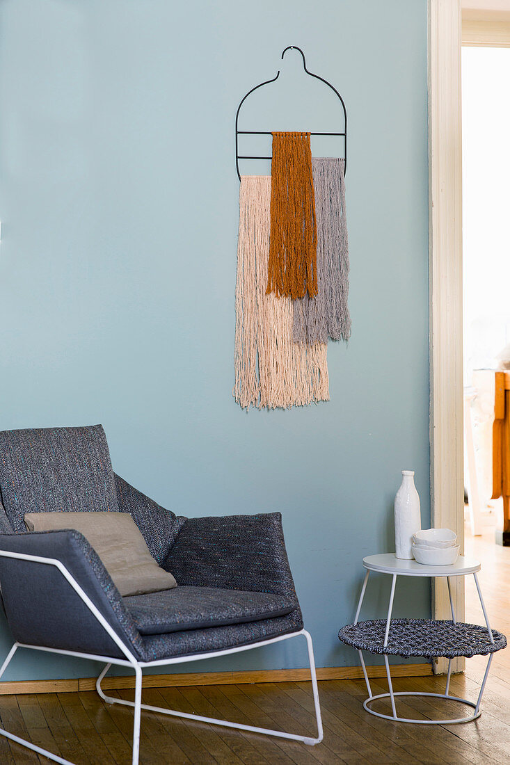 Bohemian-style wall hanging of woollen tassels above modern armchair