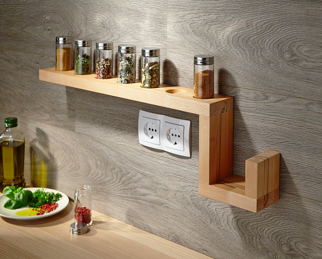 Wall-mounted shelf for spice jars on wooden kitchen wall