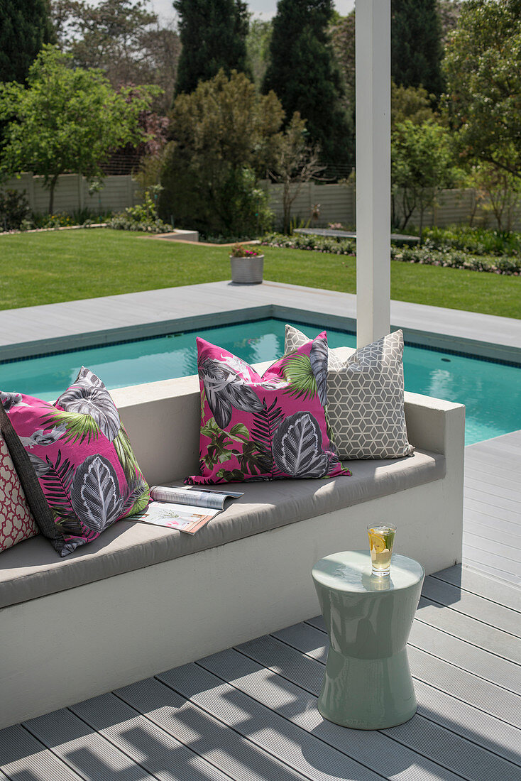 Scatter cushions and seat cushions on outdoor sofa on terrace next to pool