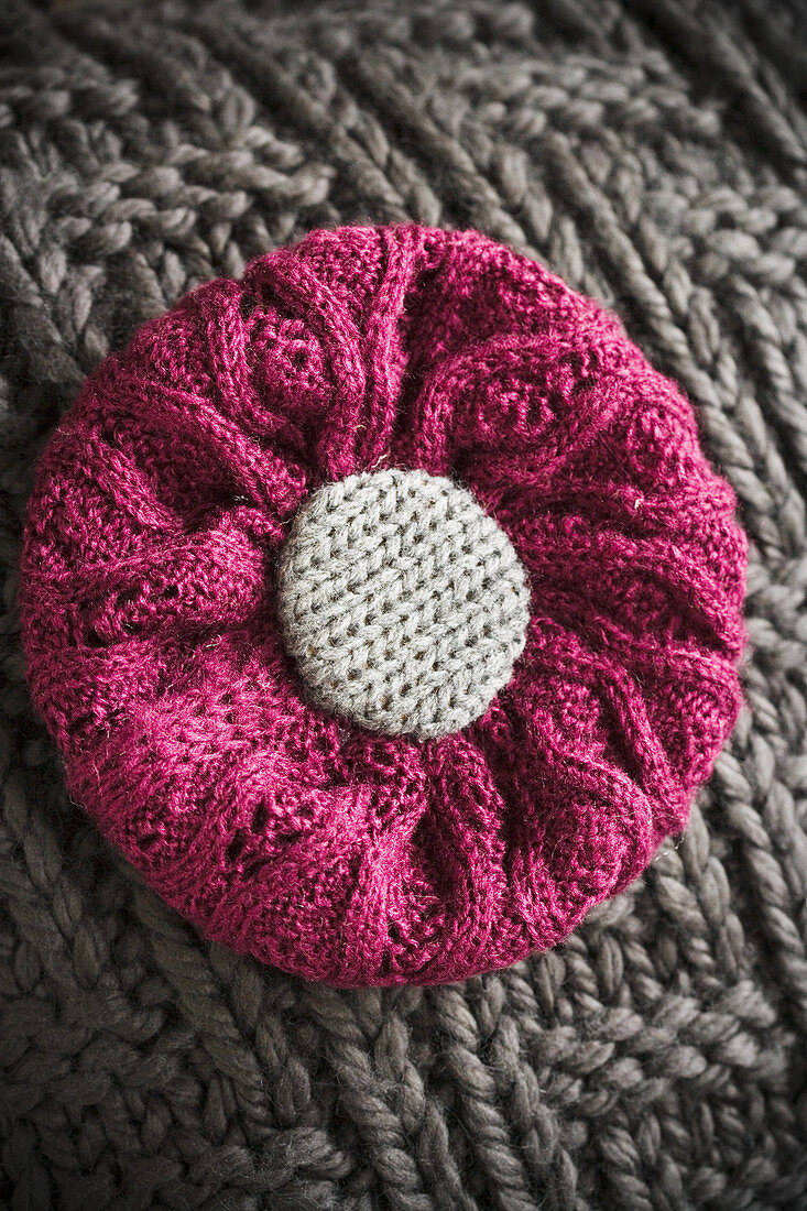 Cushion with knitted cover and knitted flower