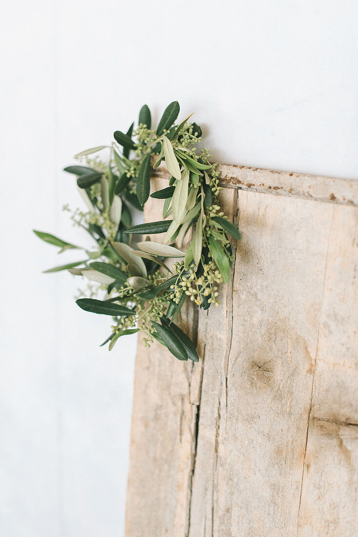 Wreath of flowering olive branches on wooden board
