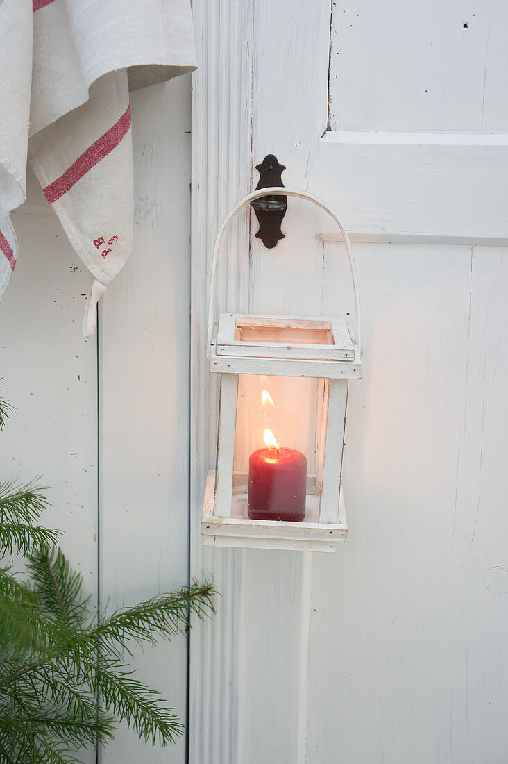 Laterne mit brennender Kerze an einer Holztür