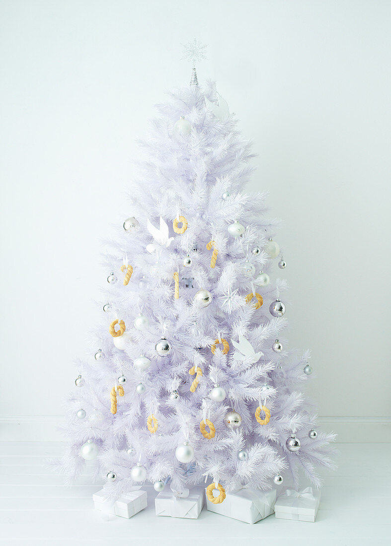 Künstlicher weißer Weihnachtsbaum mit Gebäck und Kugeln als Schmuck