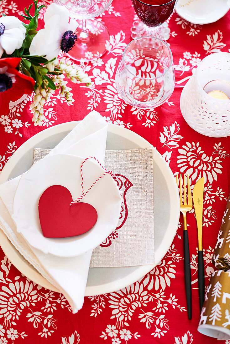 Festliches Gedeck mit Herzdekoration auf rot-weisser Tischdecke