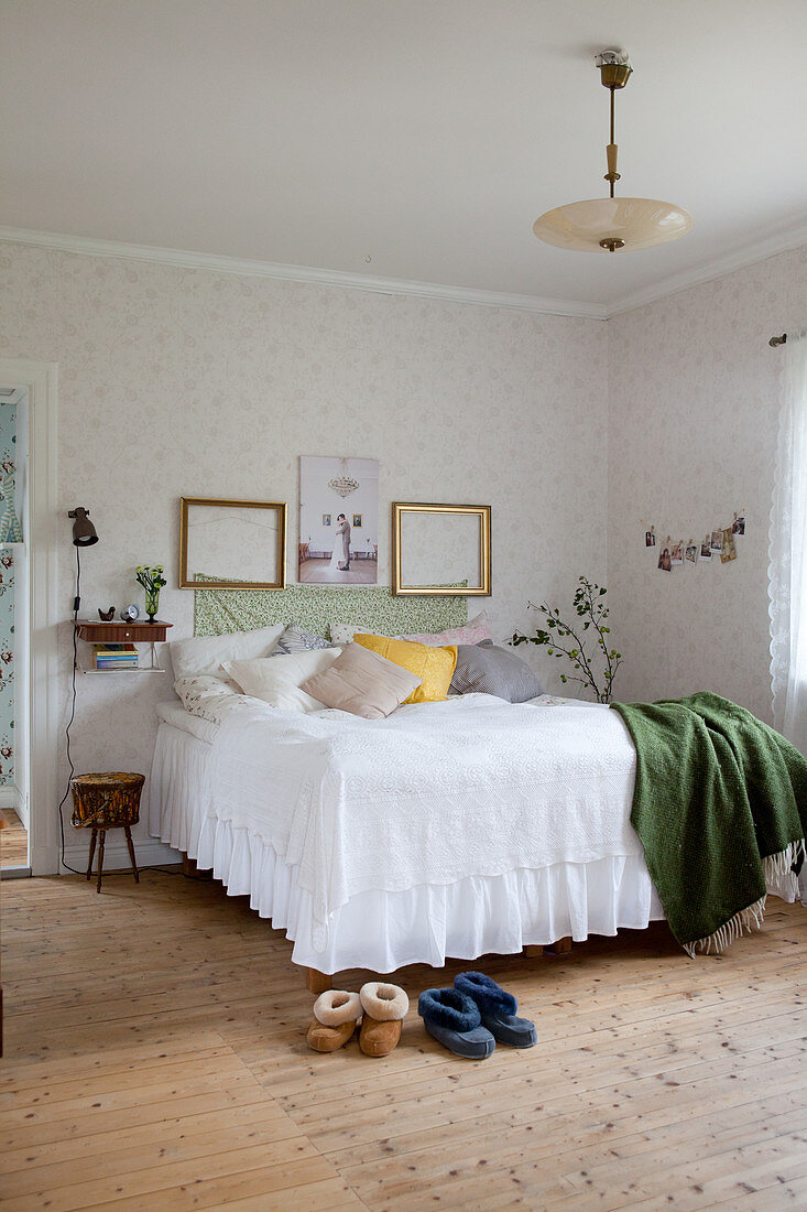 Bed with valance in vintage-style bedroom with board floor