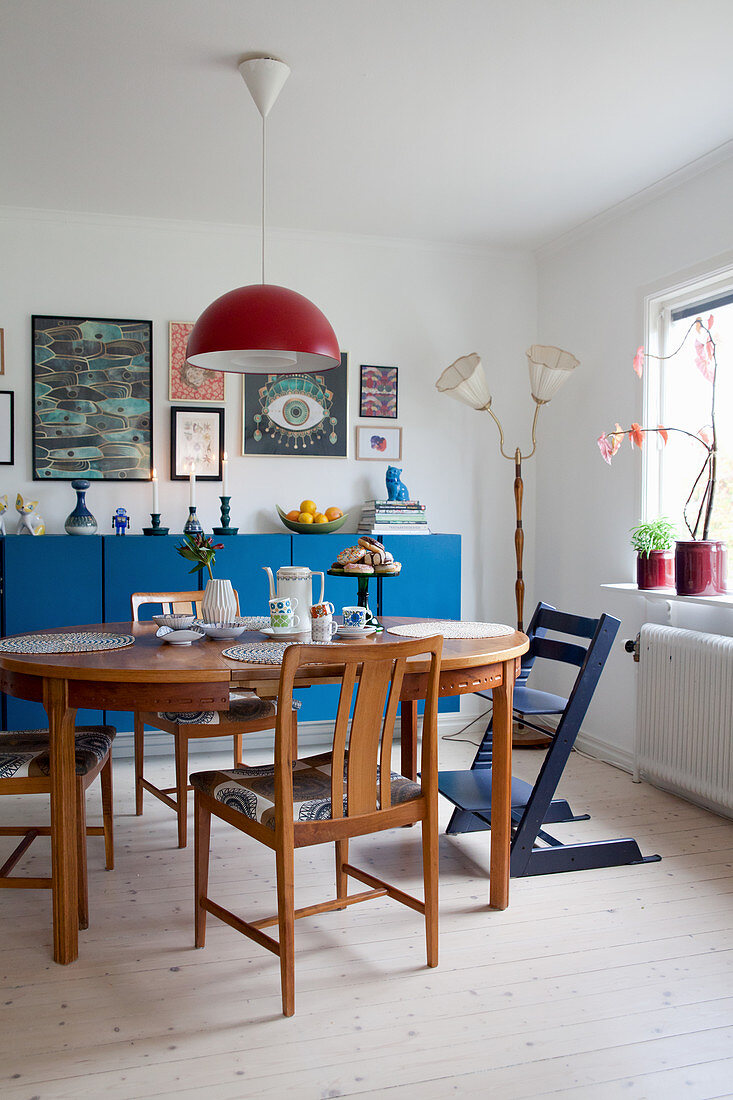 Holztisch mit Stühlen vor blauem Sideboard im Esszimmer