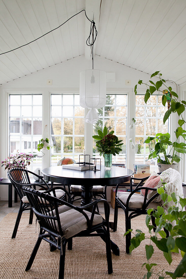 Runder Tisch mit Stühlen und Zimmerpflanzen im Wintergarten