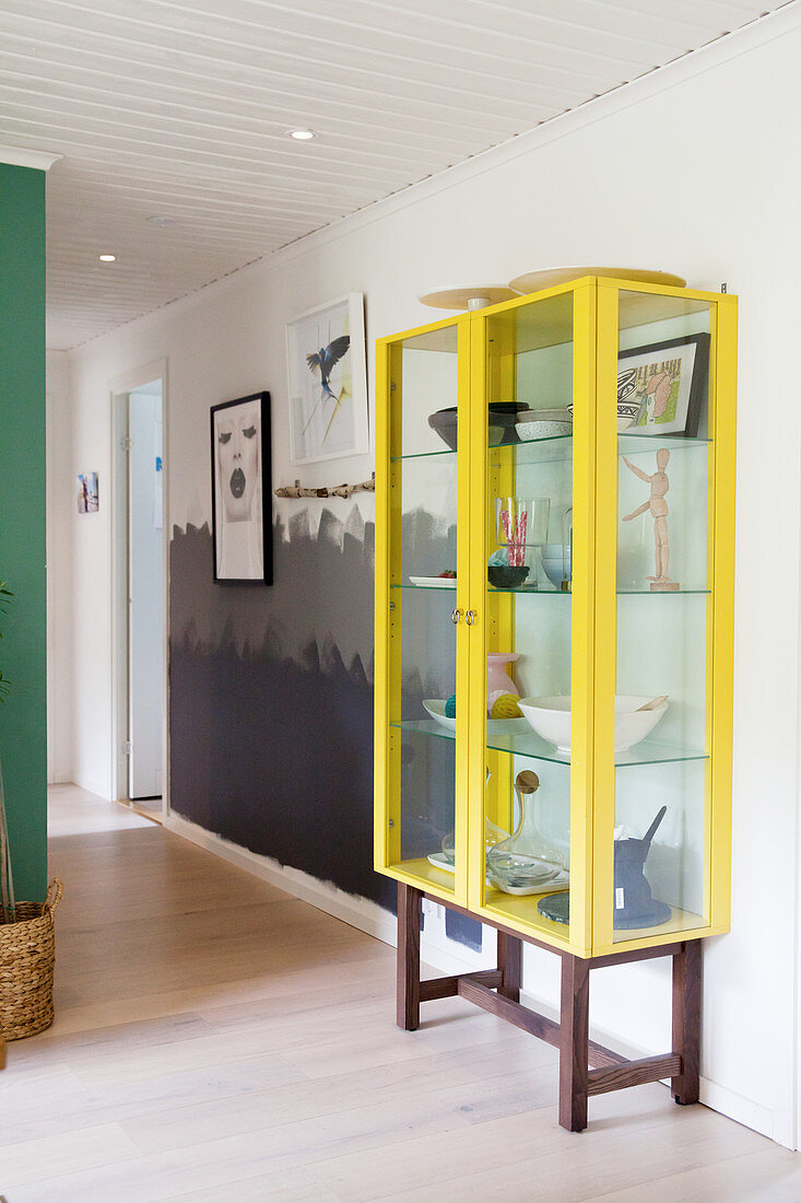 Yellow display cabinet in hallway with wall painted in three shades