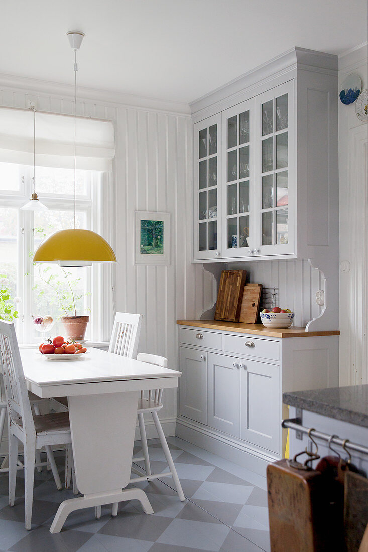 Hellgraue Anrichte und weißer Holztisch mit Stühlen in Wohnküche