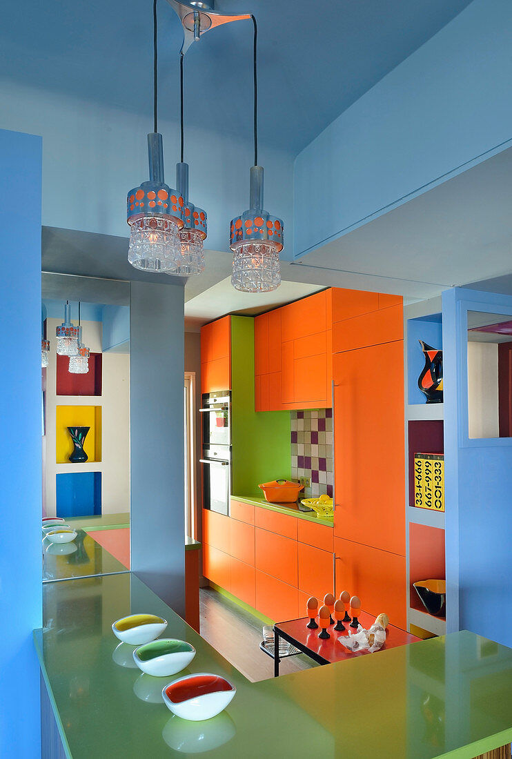 Orangefarbener Schrank und grüne Frühstückstheke in Küche mit blauen Wänden