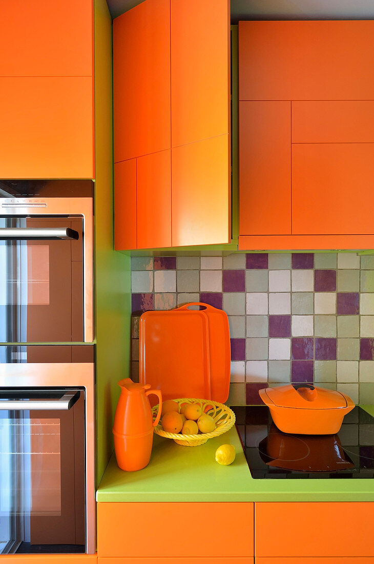 Orangefarbener Küchenschrank mit grüner Arbeitsplatte und Einbaugeräten