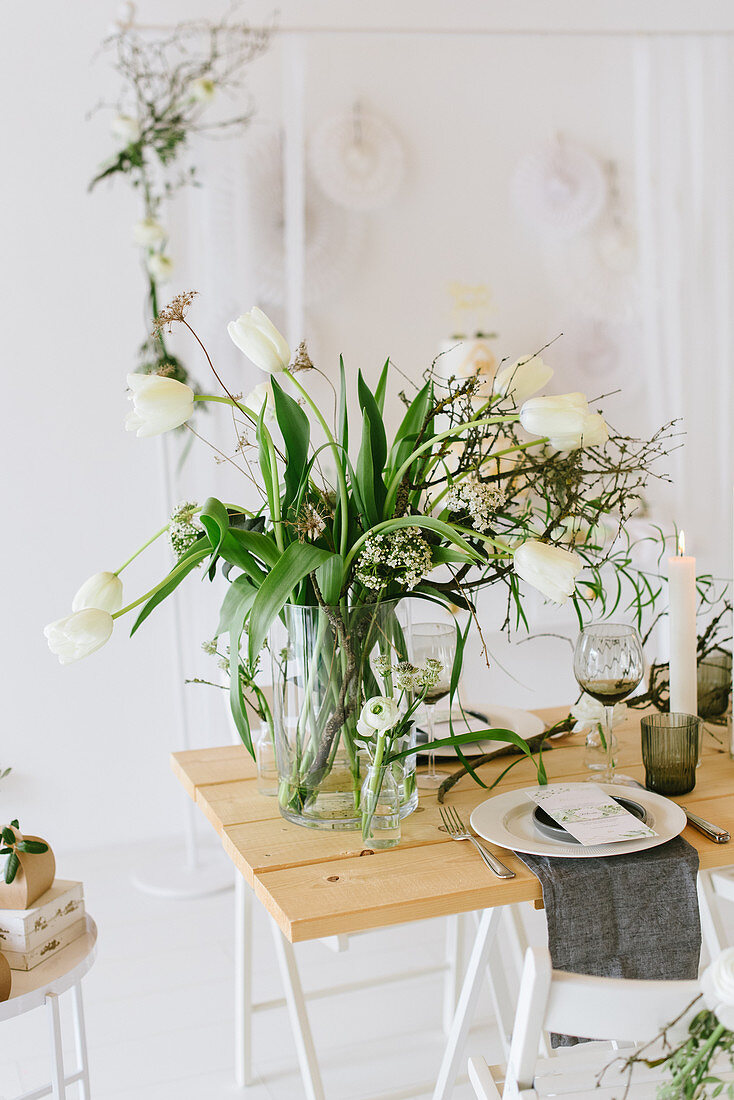 Gedeckter Hochzeitstisch mit Tulpenstrauß, trockenen Zweigen und Cylinderkerzen