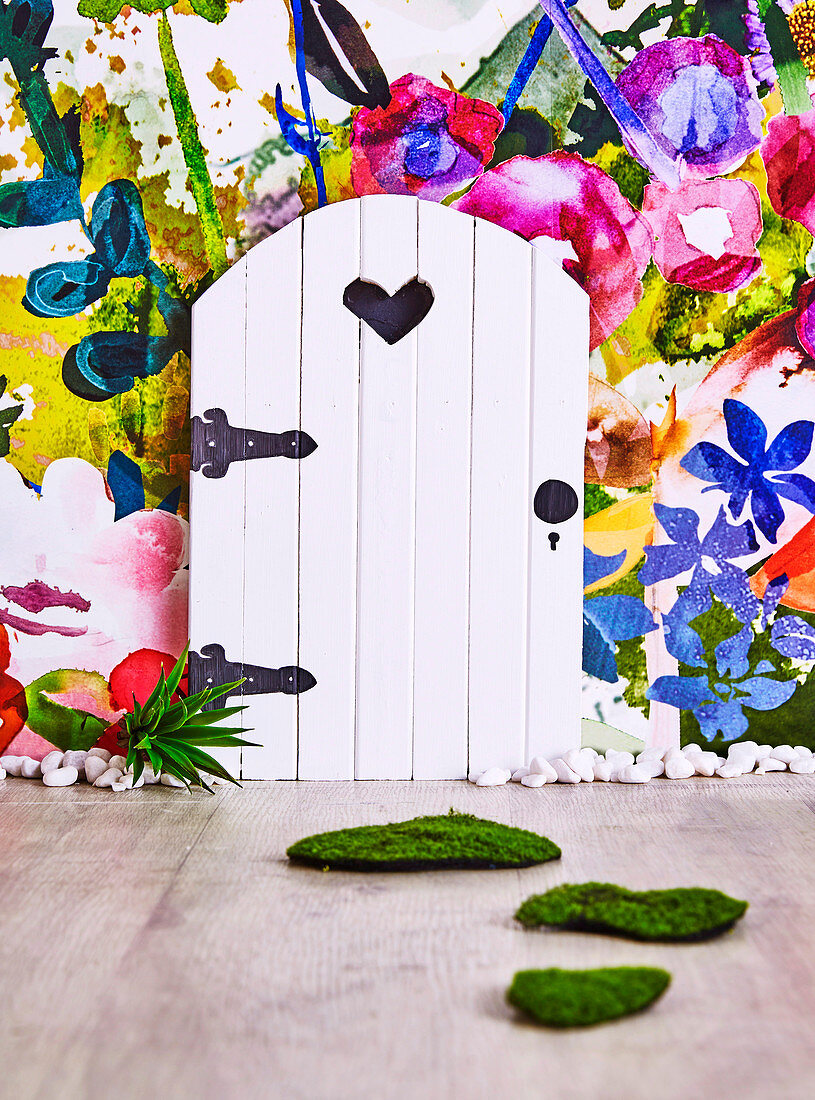 Kleine Holztür vor Vliestapete mit Blumenwiese im Kinderzimmer