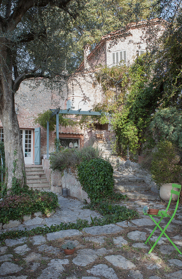 Grüner Gartenstuhl im Hof eines mediterranen Steinhauses