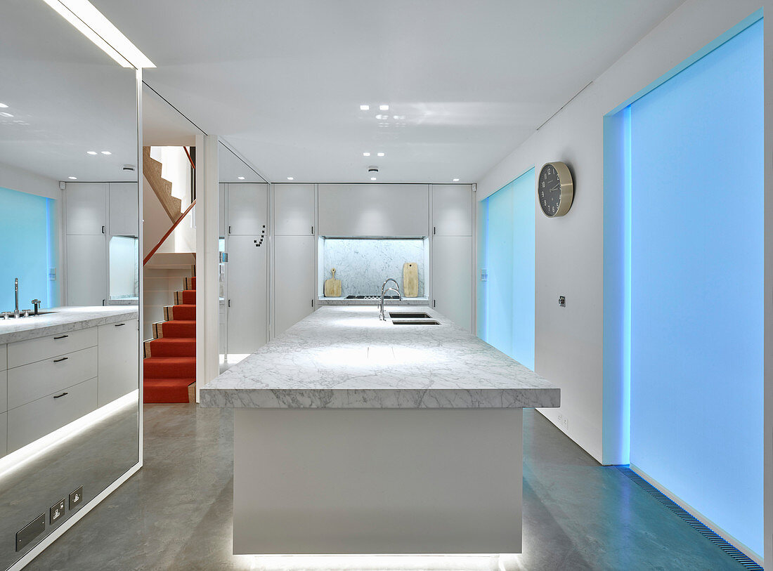 Island counter with marble top, mirrored walls and blue lighting in elegant kitchen