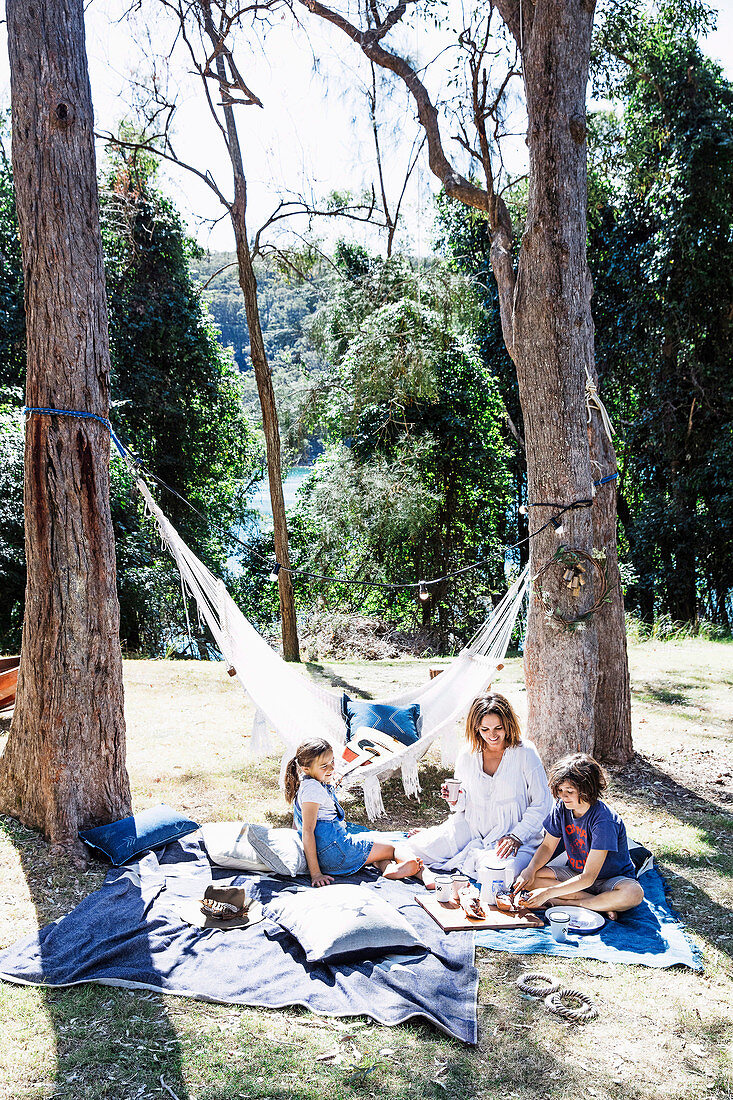 Familie beim Picknicken unter hohen Bäumen im Garten