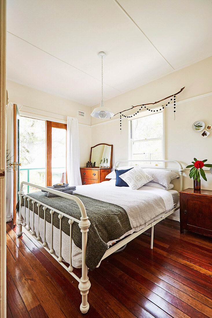 Doppelbett im Schlafzimmer mit Balkon und rustikalem Dielenboden