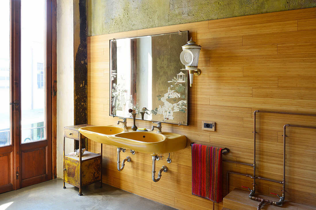 Twin sinks, mirror and wall lamp on wood-panelled bathroom wall