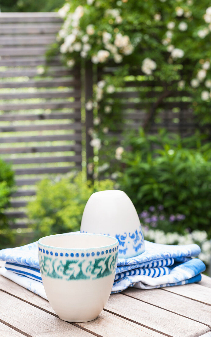 Zwei Tassen mit grün-blauem Ornament auf dem Gartentisch