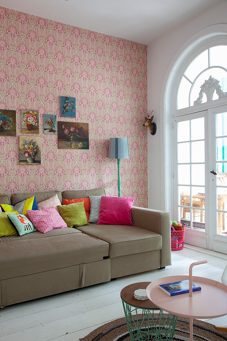 Scatter cushions on sofa in living room of period apartment with patterned wallpaper