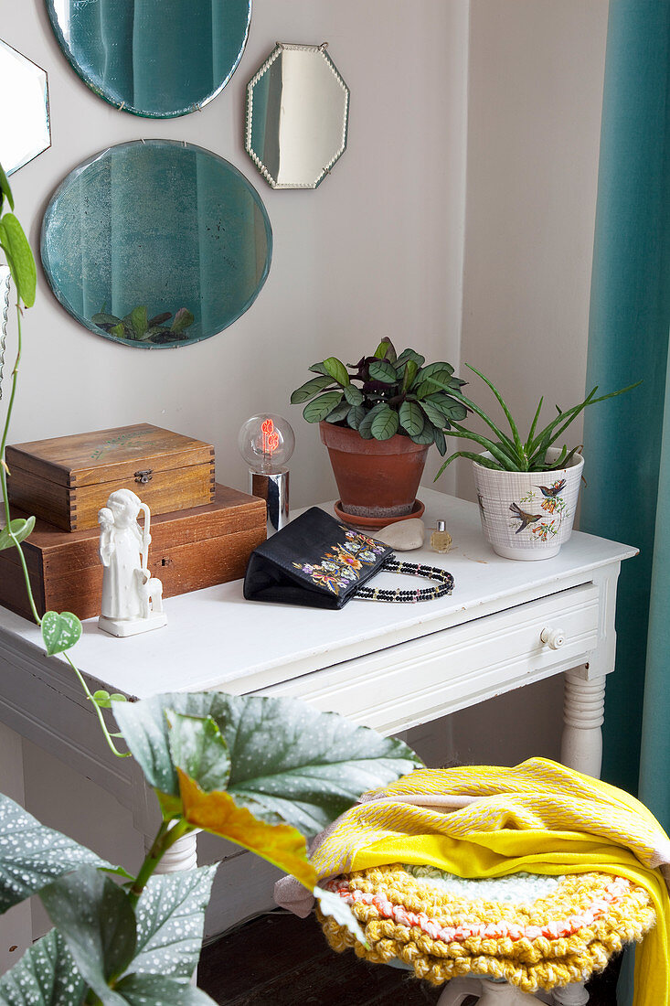 Schubladentisch mit Zimmerpflanzen, Handtasche, Holzkästchen und Figur