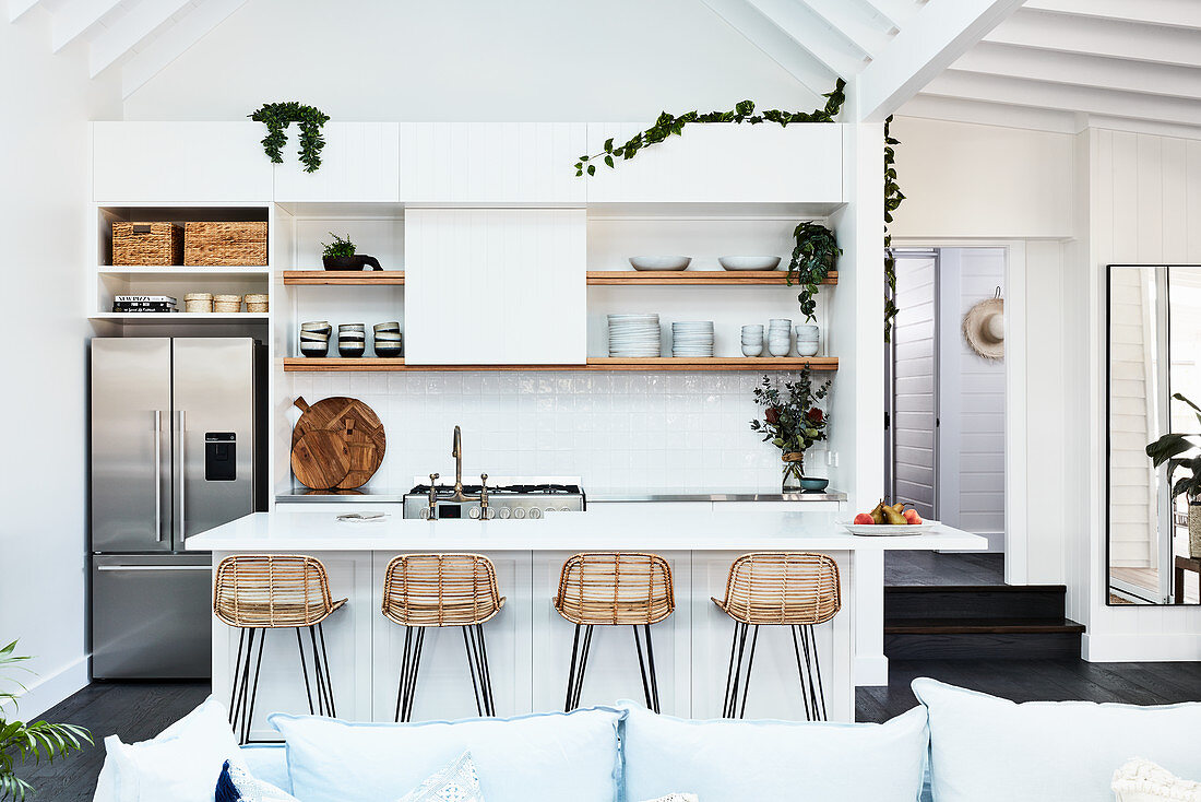 Blick über Sofa auf weiße Kücheninsel in offenem Wohnraum