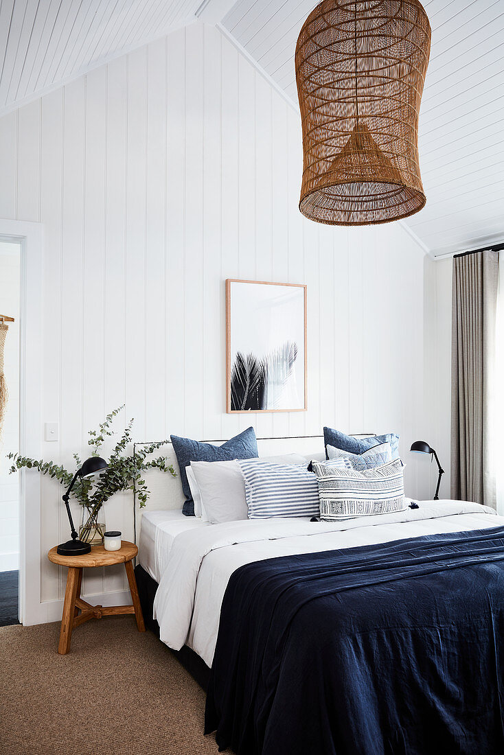 Blue bedspread on double bed with white wood-clad walls