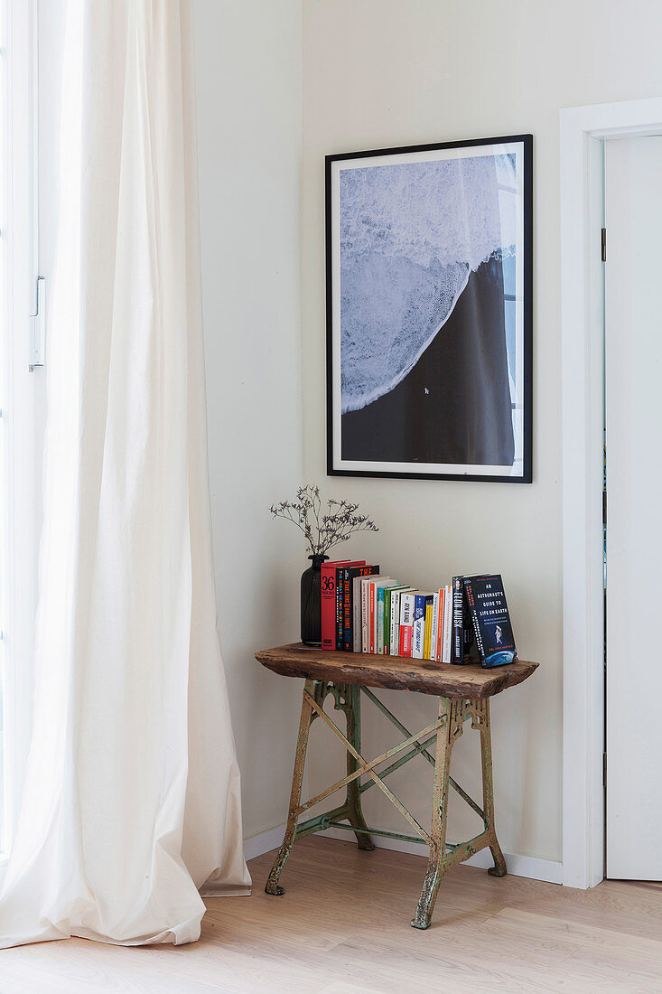 Books on rustic console table below picture on wall