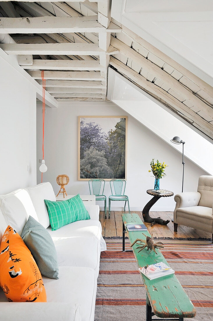 Weißes Sofa mit bunten Kissen und rustikale Holzbank als Couchtisch im Wohnzimmer