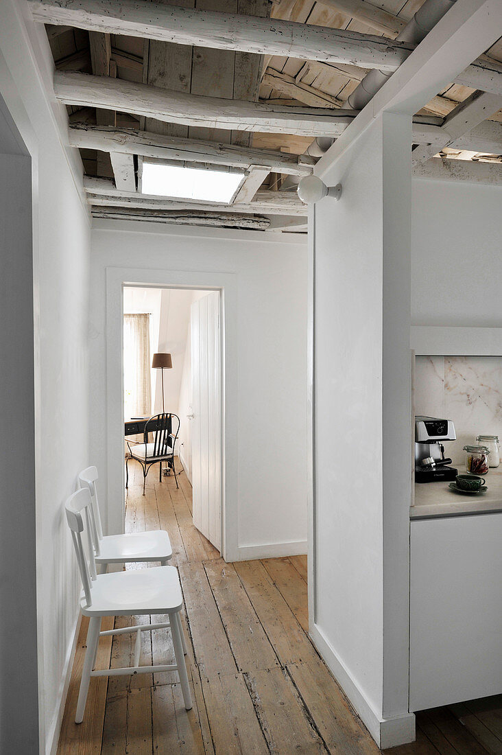 Stühle auf rustikalem Dielenboden und Küche in offenem Wohnraum