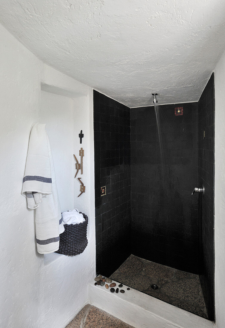 Shower area with black tiles in white bathroom