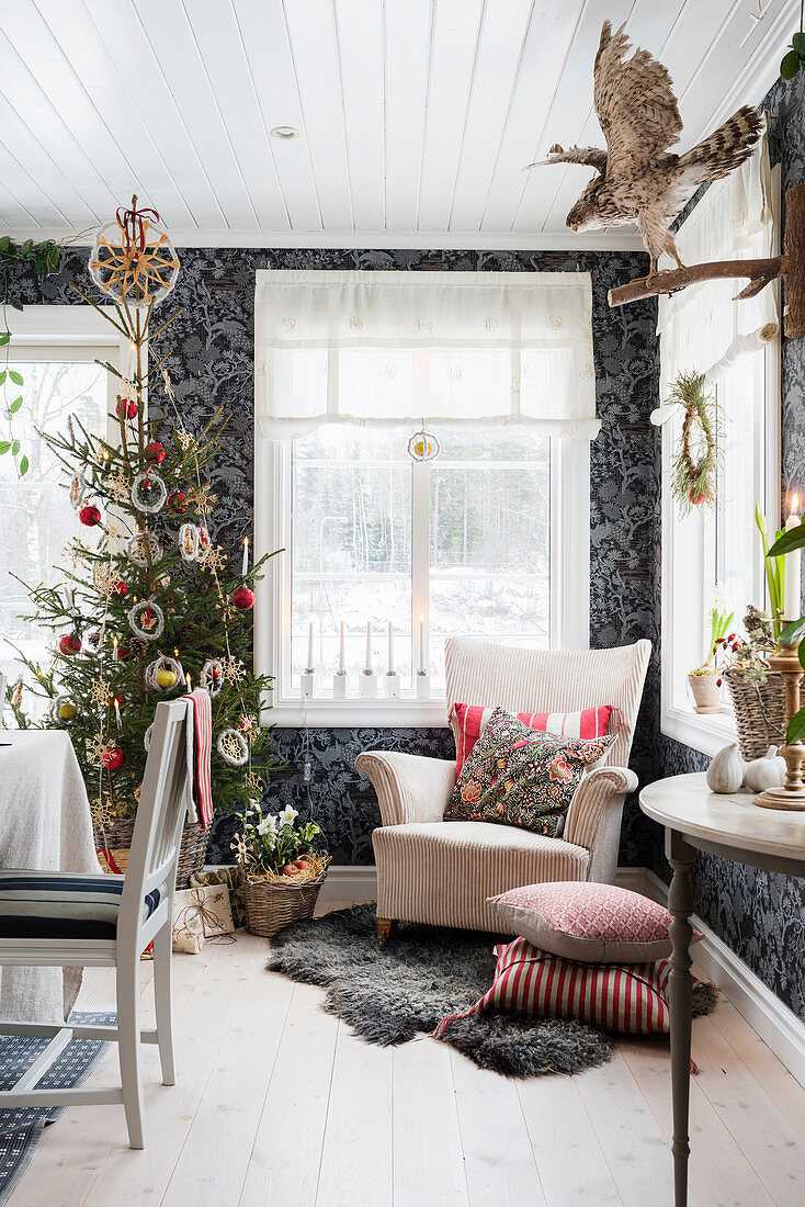Armchair and Christmas tree against black patterned wallpaper