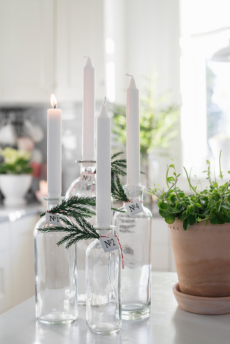 DIY candlesticks made from glass bottles decorated with fir sprigs