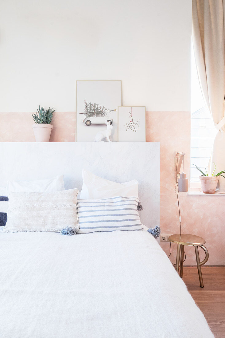 Bed with marbled headboard in bedroom in pastel shades