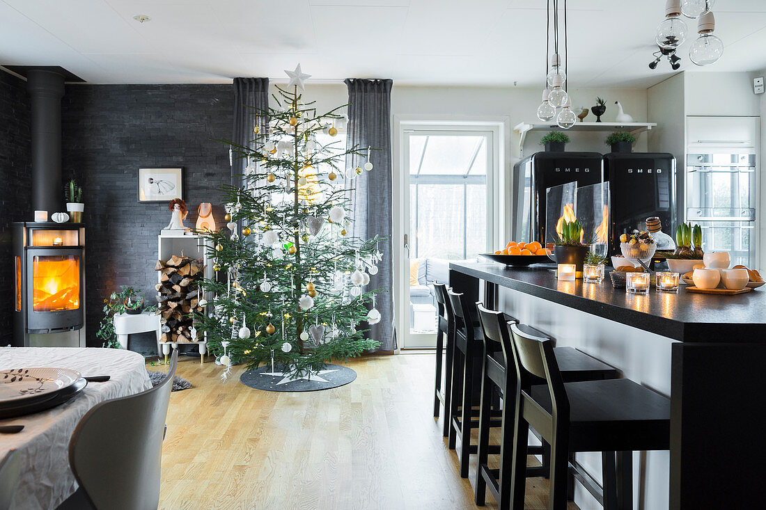 Elegante Kücheninsel, im Hintergrund Weihnachtsbaum und Kaminofen in offenem Wohnraum