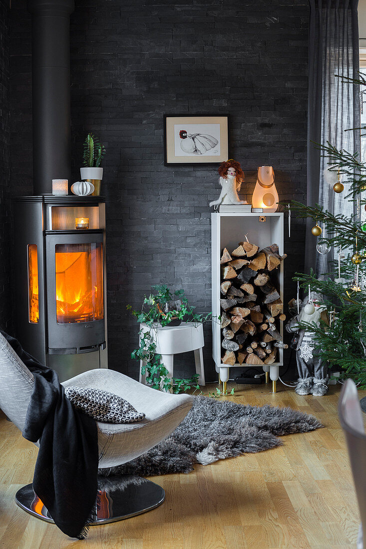 Log burner and stacked firewood in living room with slate-clad wall