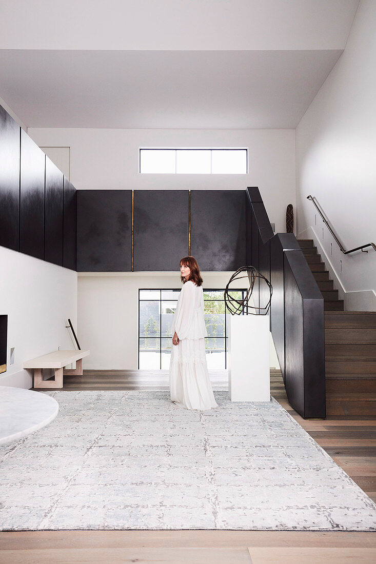 Elegant, minimalist hall with stairs, woman in white dress