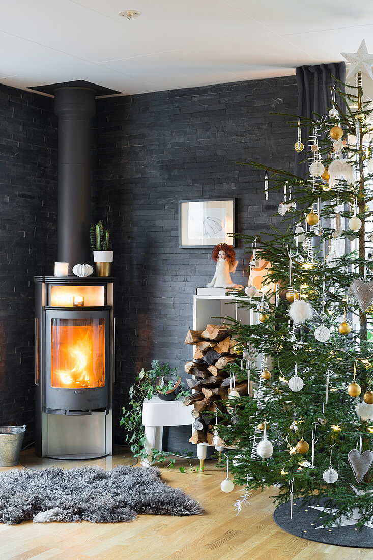 Kaminofen und Weihnachtsbaum im Wohnzimmer mit Schieferplatten als Wandverkleidung