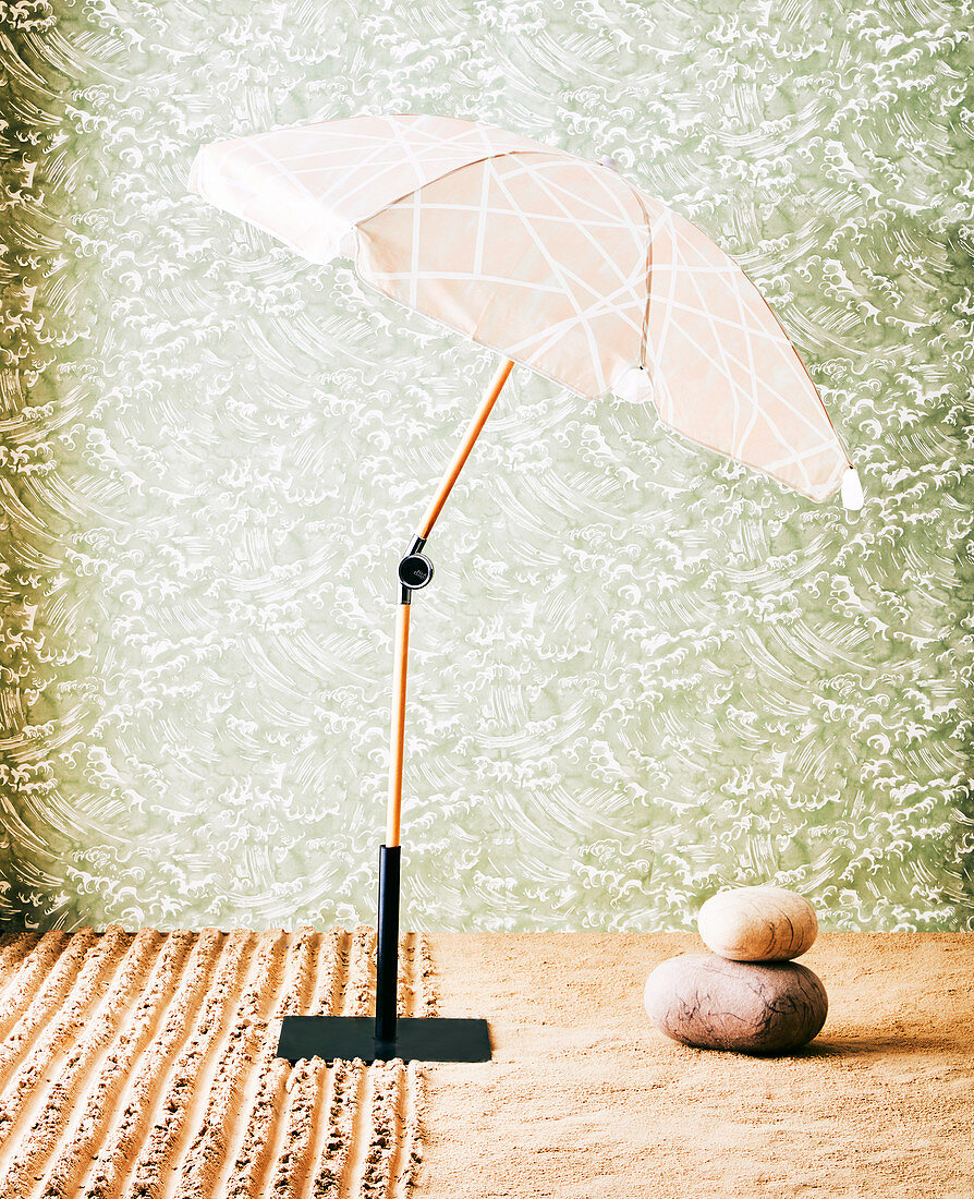Sonnenschirm mit Schirmständer und Natursteine vor tapezierter Wand