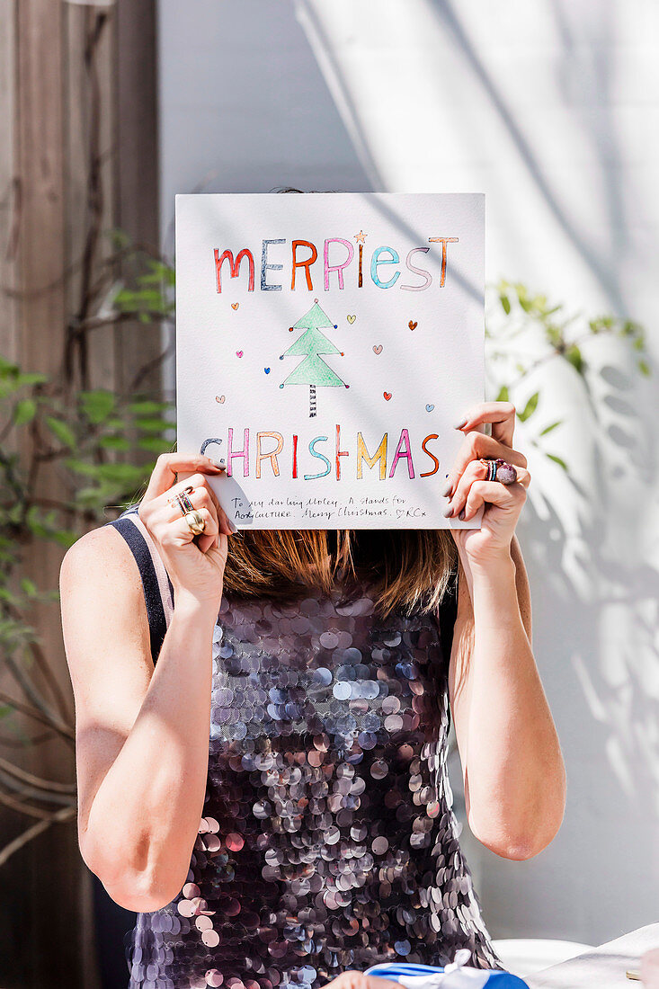 Woman holds Christmas greeting in front of her face