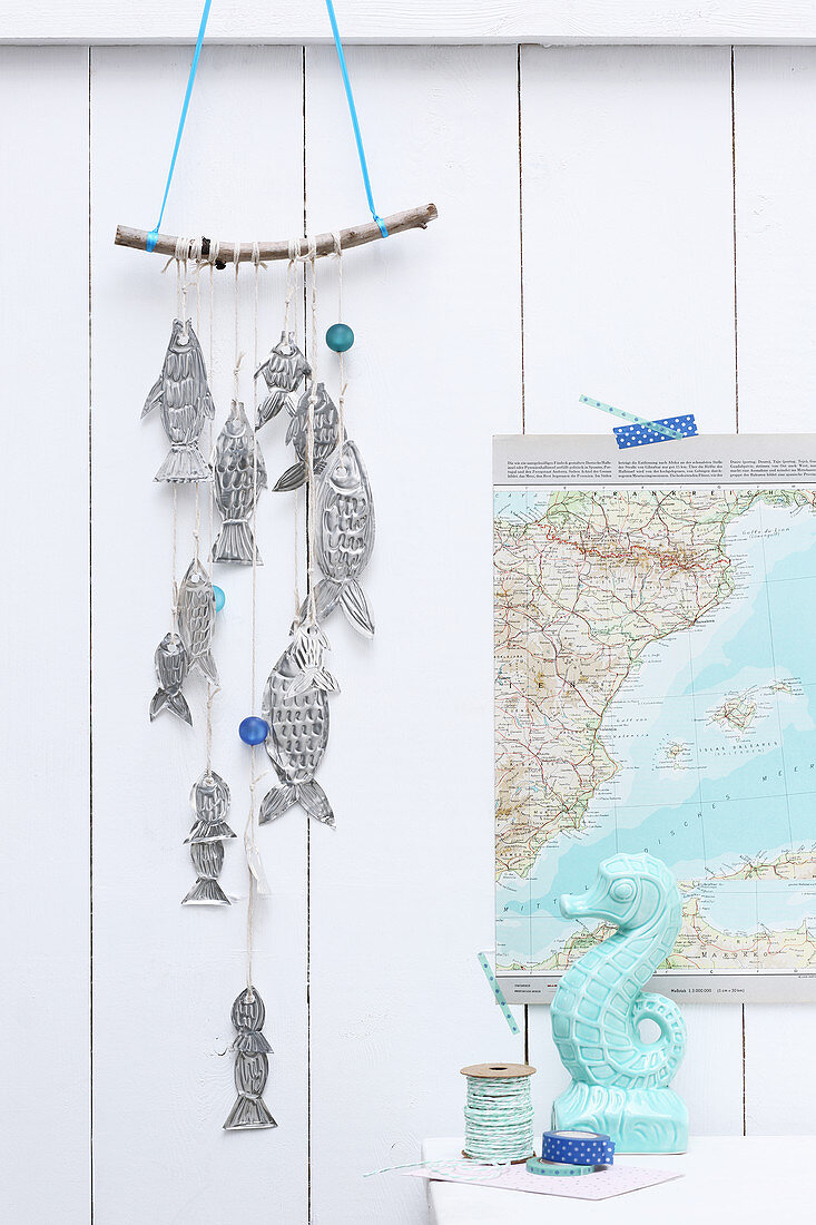 Mobile of hand-made metal fish hung on board wall