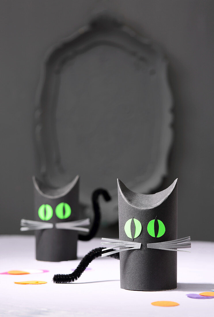Cats made from grey-painted toilet-paper tubes with green eyes