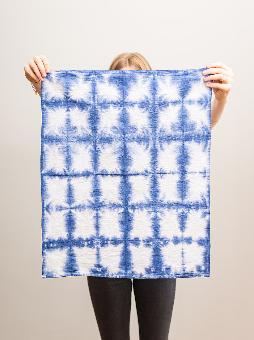 A woman holding a tea towel dyed using the shibori technique