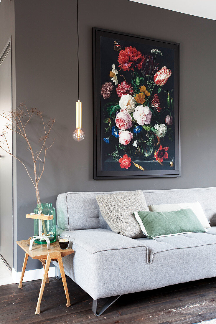 Grey sofa with scatter cushions, side table, pendant lamp and floral painting