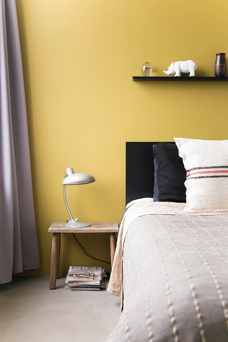 Gelbe Wand hinter dem Bett im Schlafzimmer