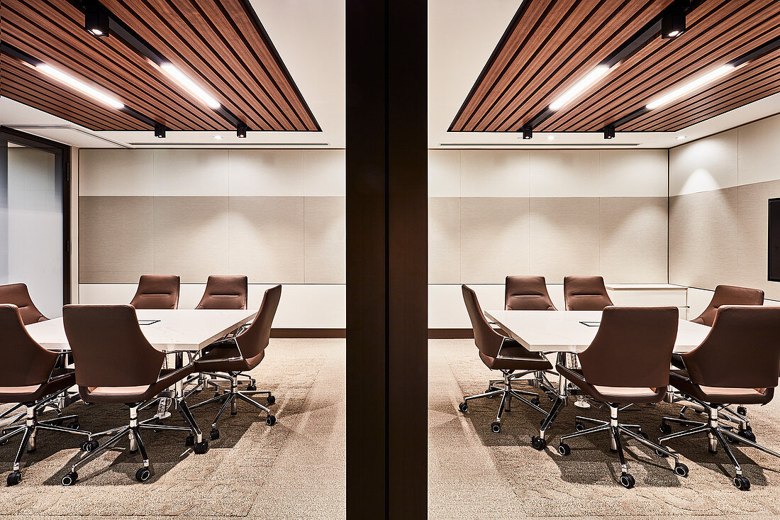 Eleganter Konferenzraum mit zwei Tischen und rollbaren Stühlen in Brauntönen