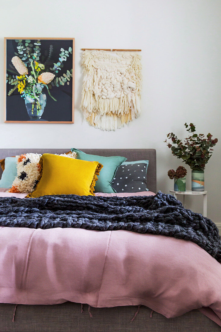Picture and macrame over the bed with various boho-style pillows