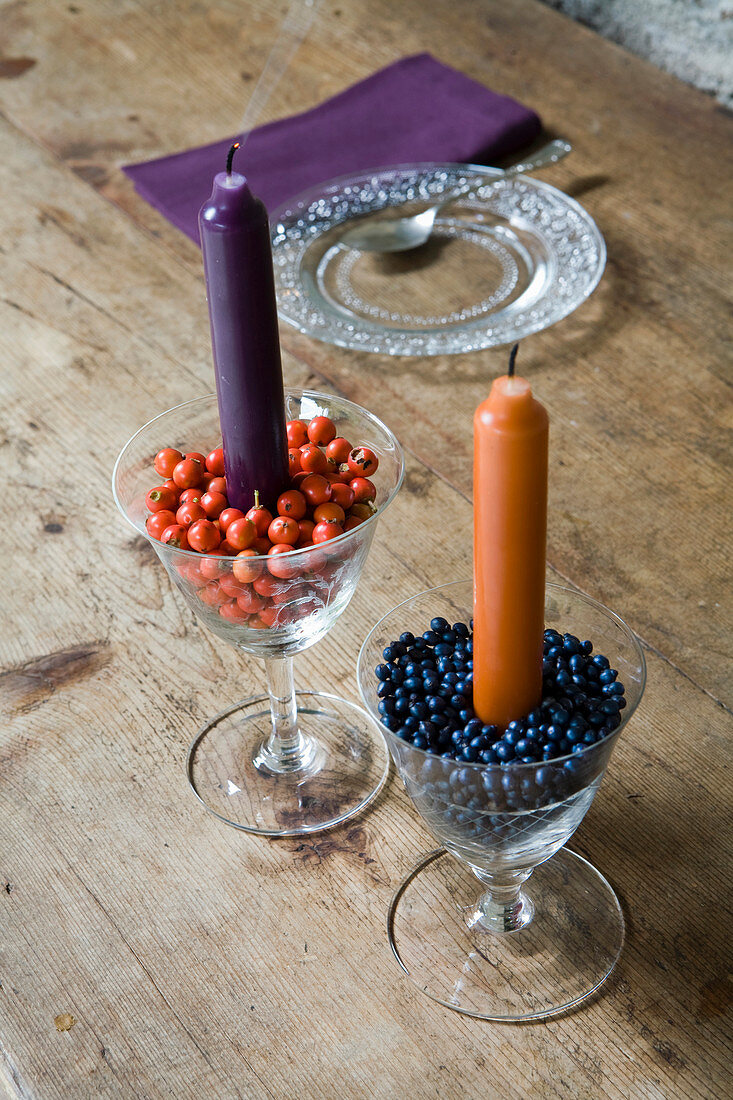 Kerzen in mit Hagebutten und Schneeballbeeren gefüllten Glasschalen